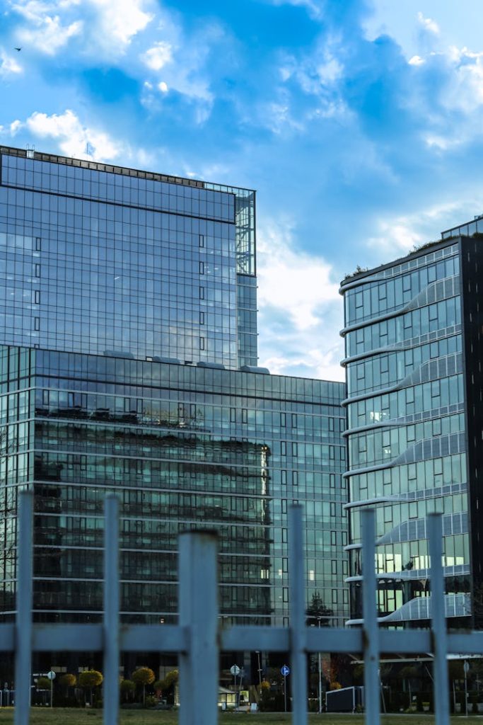 Glass facade office buildings reflecting a vibrant blue sky with clouds. Urban architectural style.