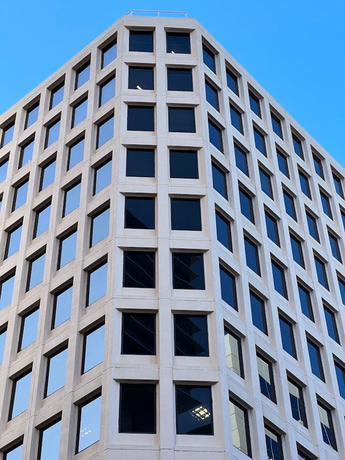 Low-angle view of a modern office building facade in Sydney, Australia, showcasing glass windows and unique architecture.
