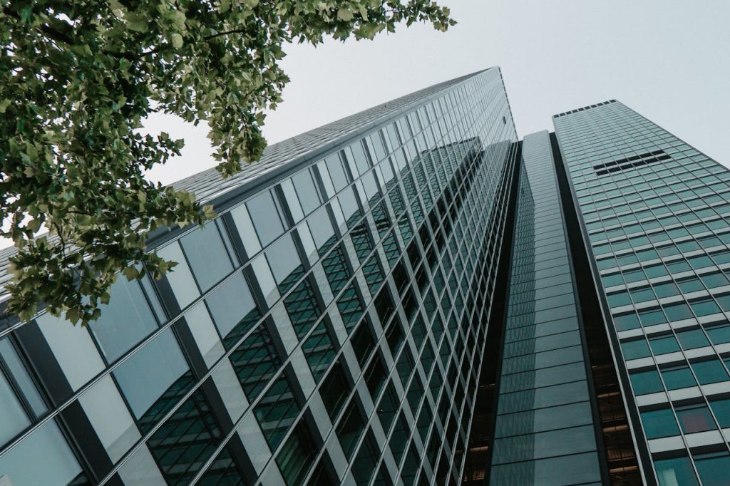 Low angle shot of tall skyscrapers surrounded by lush green leaves, capturing urban architecture.